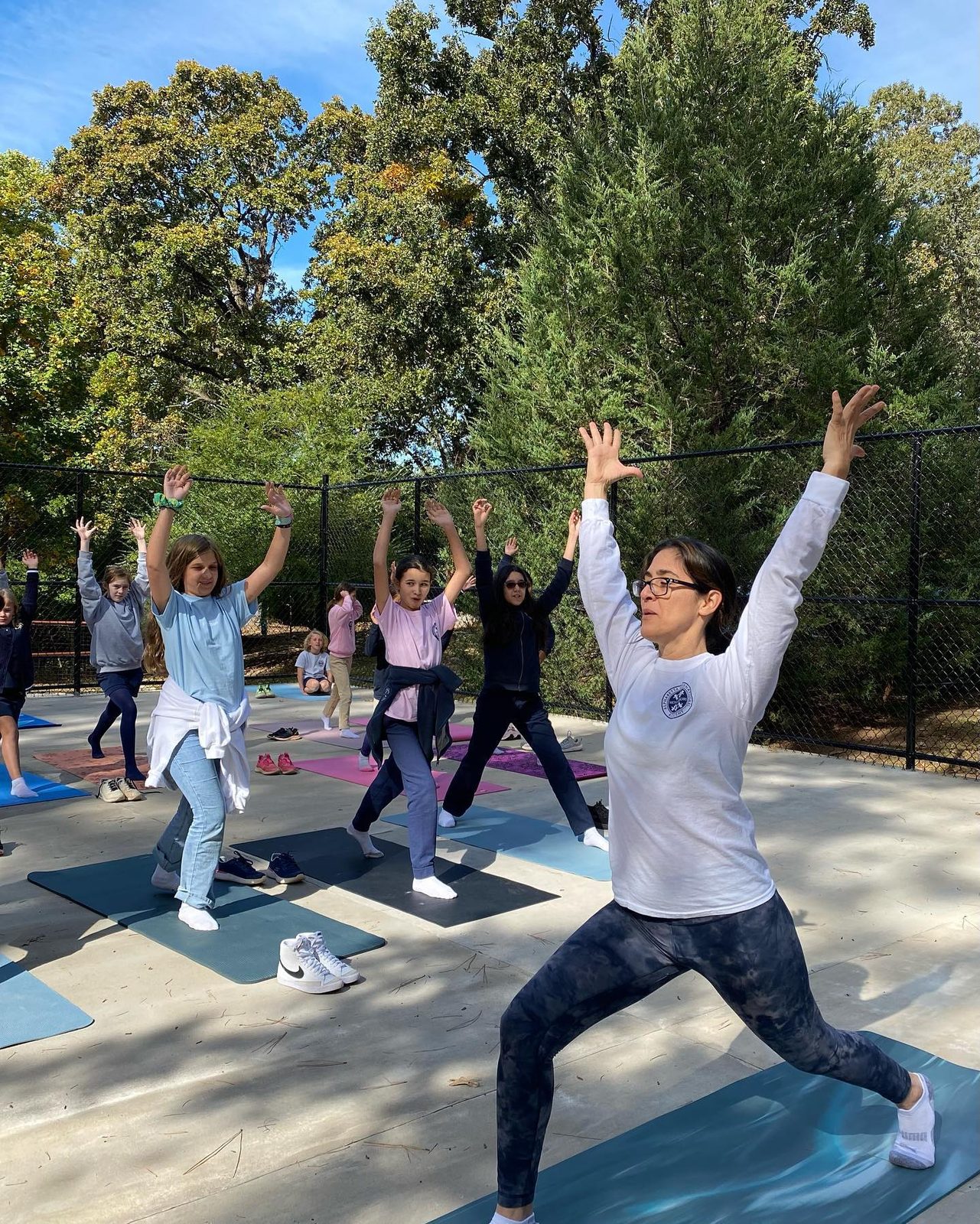 An AIA instructor leading students in an outdoor yoga class on the campus court