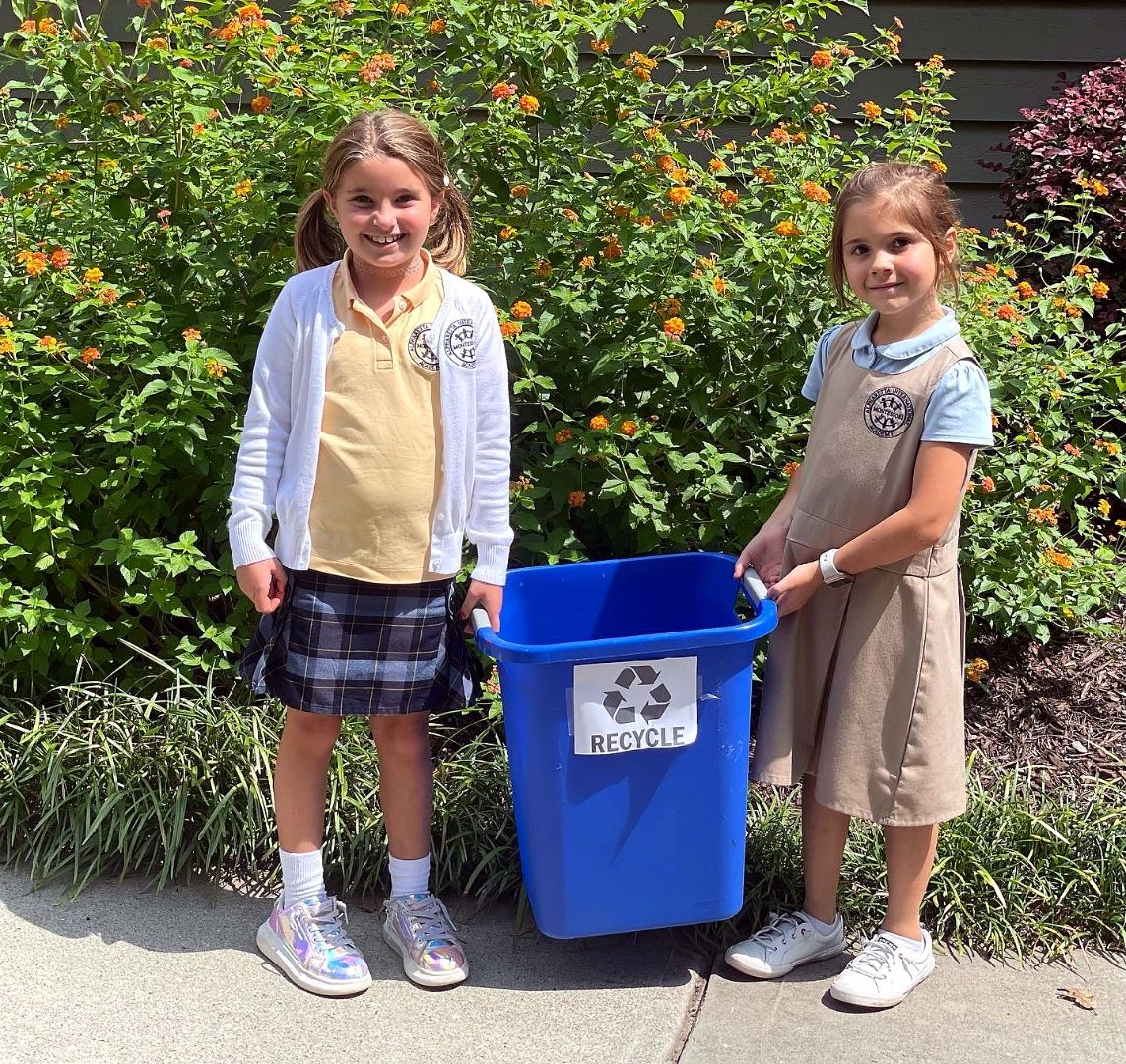 Two AIA students caring for the campus by recycling near the garden beds