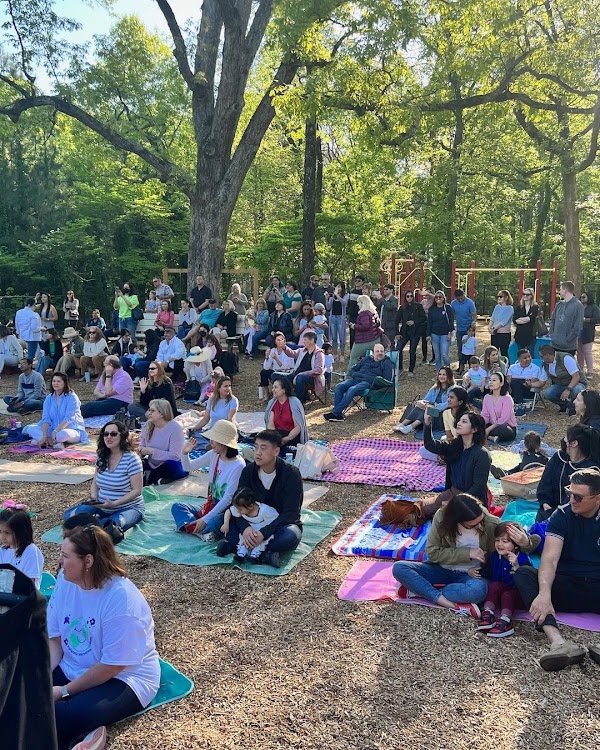 Families on picnic blankets watching a movie outdoors on the school lawn