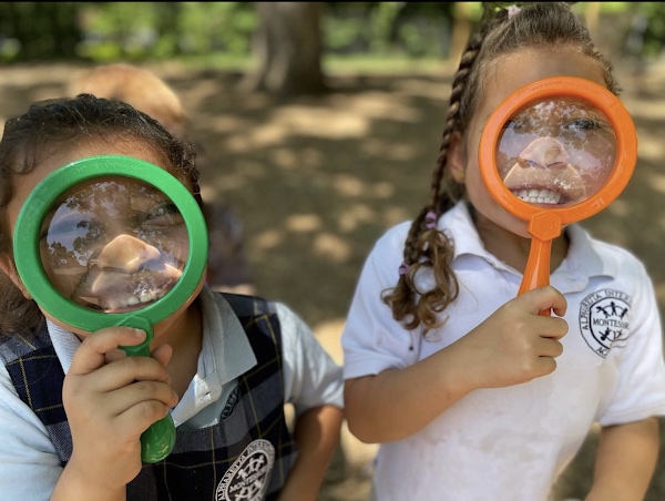 AIA students using magnifying glasses to explore nature outdoors