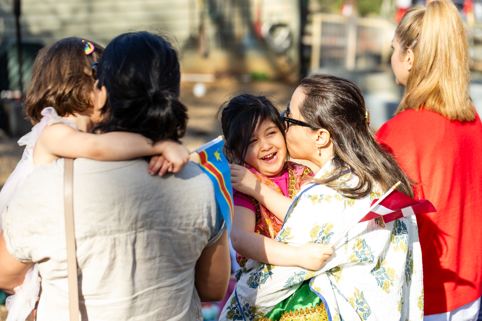 A parent warmly embracing their smiling child at an AIA community gathering