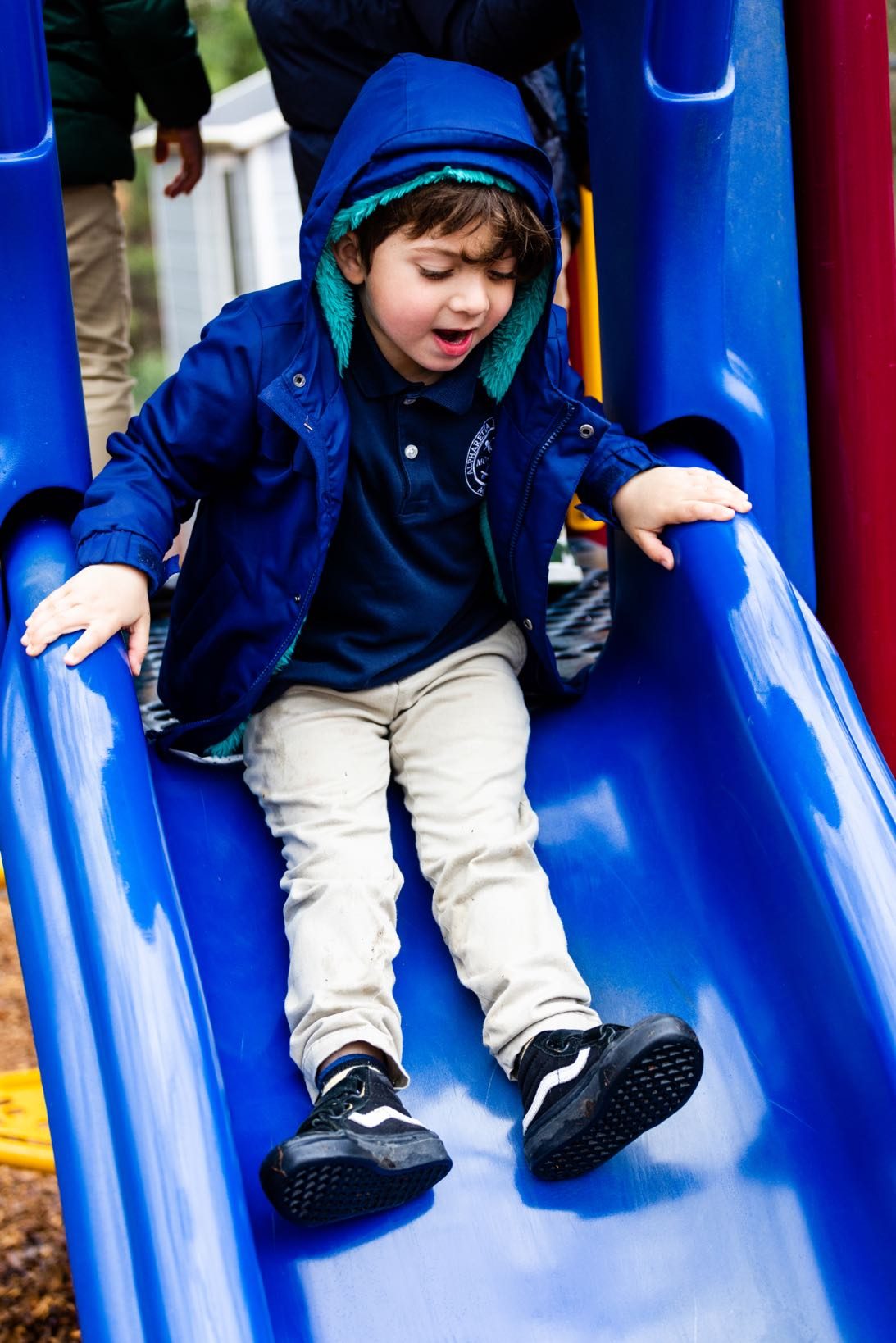 A Pre-Primary child laughing on the playground slide